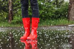 雨天站在户外穿着红色橡胶靴的女人带着冰雹和特写