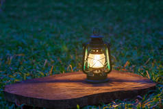 antique kerosene lamp with lights on the wooden floor in the lawn at night