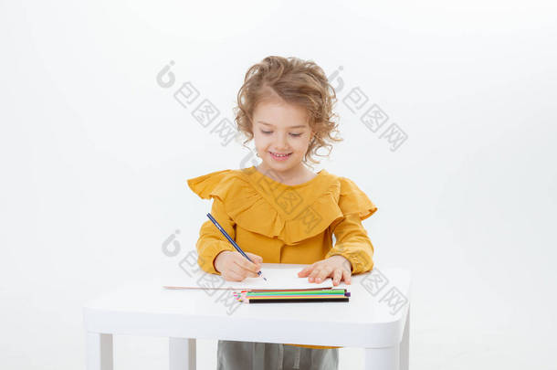 一个可爱的小女孩，拿着铅笔在桌子边画画，铅笔被白色背景隔开了