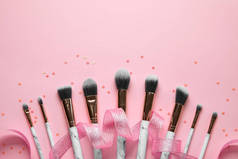 一套粉色背景的化妆品刷和彩带