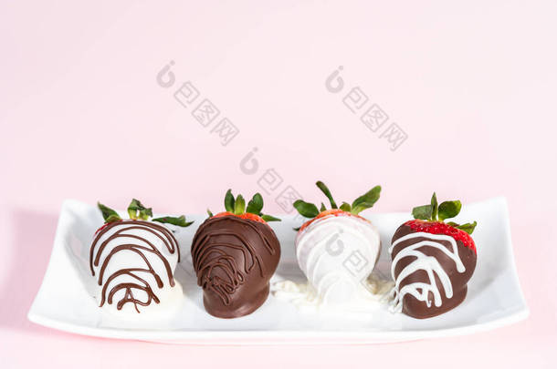 白巧克力和黑巧克力蘸草莓在白盘上.