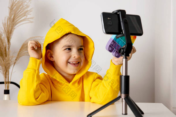 可爱可爱的小男孩博客记录生活方式博客，在三脚架上对着智能手机摄像机说话。年轻的影响者为他的频道拍摄<strong>vlog</strong> 。孩子在网上为他的追随者制作视频.