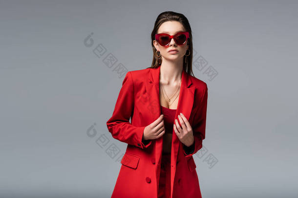 穿着时髦红色西服、戴着<strong>墨绿</strong>色太阳镜的年轻模特