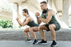 户外运动夫妇和健身训练。男子和妇女在街头锻炼时蹲着.