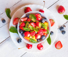 新鲜的夏季草莓，蓝莓和薄荷叶，木制背景