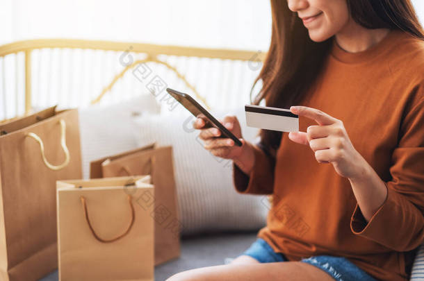 一个漂亮的年轻女子用手机和<strong>信用卡</strong>在网上购物的照片
