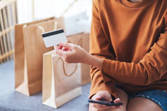 持用购物袋在家中持用信用卡进行网上购物的女性形象