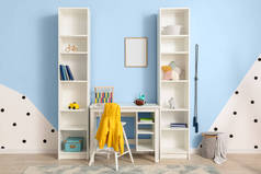 Table with rugby ball and shelf unit with toys near color wall in children's room