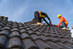 2 roofers working on the working at height to install the Concrete Roof Tiles on the new roof of new