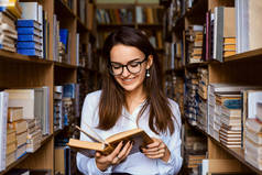 图书馆里快乐的女学生。高校图书馆文学系具有吸引力的高加索女学生阅读小说