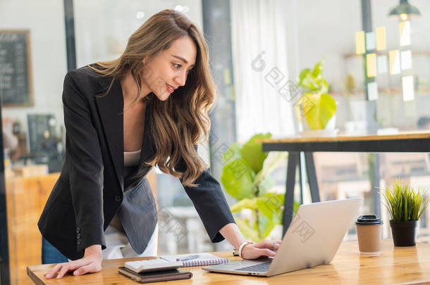 年轻的女商人正在看笔记本电脑上的财务数据。她正在分析、计算、研究一位初创女性的财务文件。财务管理概念