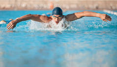 a handsome young male athlete swimming in an olympic-sized pool.