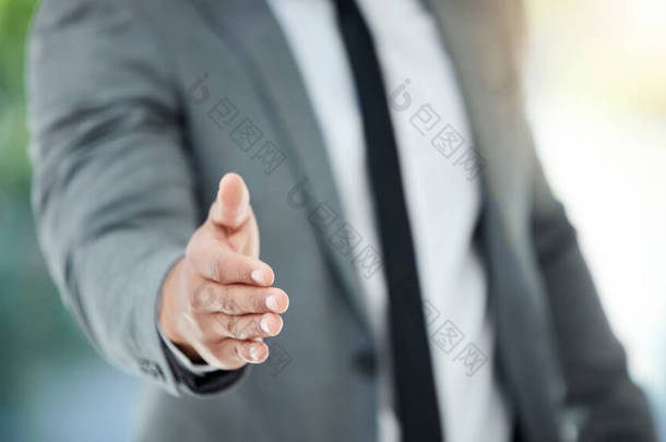 an unrecognizable businessman reaching out for a handshake while standing in his office.