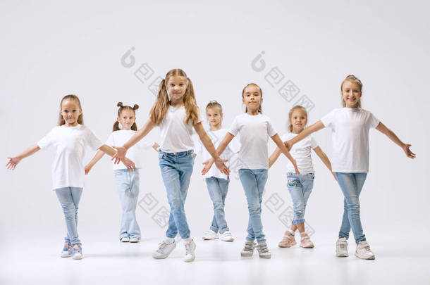 Modern choreography lesson. Dance group of happy, active little girls in jeans and t-shirts dancing 