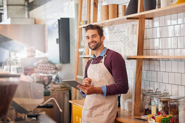 Coffee inspiration is never out of my reach. happy young business owner using a tablet while standin