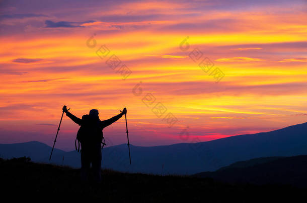 在<strong>山顶</strong>上举着胳膊的远足妇女享受着她的成就。游客可以看到<strong>山顶</strong>的落日的颜色.