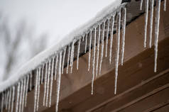 屋顶上有雪和屋顶边缘有冰柱的建筑物