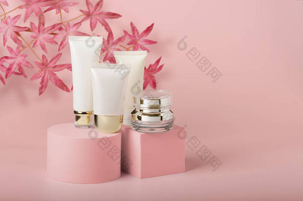 化妆品包装-产品架上的一组不同的化妆品空管的奶油和血清罐。漂亮，工作室拍摄。粉色背景的无名空白包件