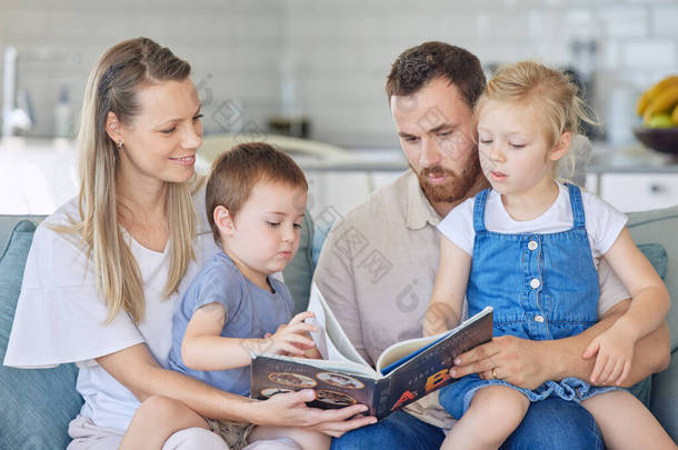 年轻的高加索家庭一起<strong>在家里</strong>的沙发上看书。母亲<strong>和父亲</strong>教他们的小<strong>儿子和</strong>女儿读书。兄弟姐妹们<strong>和</strong>父母一起学习他们的字母.