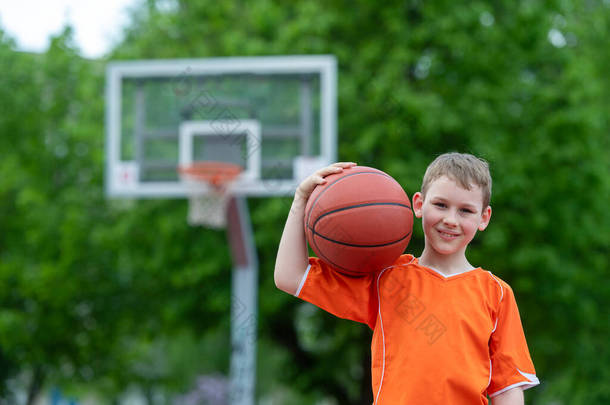 男孩在公园球场打篮球。运动生活方式,训练,露营,休闲,度假的概念.横向体育主题海报、贺卡、头饰、网站和应用程序