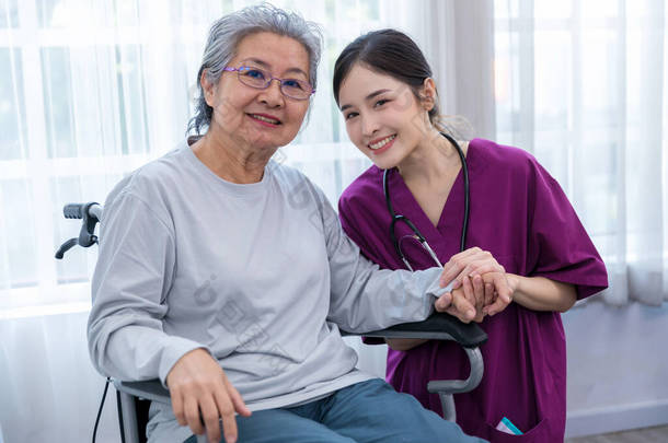 <strong>护士长</strong>照顾坐在轮椅上的一位老年病人.帮助老年妇女的护士