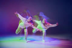 在霓虹灯下，年轻女孩在深蓝色紫色背景上跳嘻哈舞的肖像。Hobby 。运动概念、青年文化、积极的生活方式、行动、街头舞蹈
