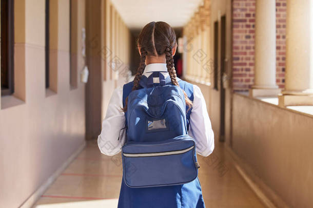 女学生、背包和步行回学校上学、上学和上早班。年轻学生的回顾步行在一个大厅，即将在校园学习，以促进青年知识的发展.