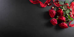 爱情与情人节的概念是用红玫瑰和黑色木制背景礼品盒制成的。顶部视图，带有复制空间，平面布局.