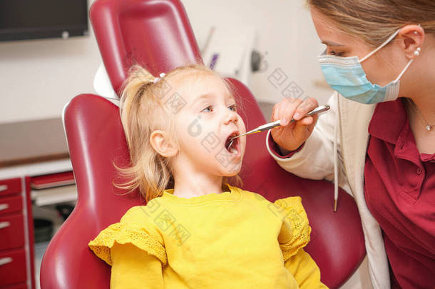 Little girl at the dentist. The doctor checks and <strong>ex</strong>amines the child's teeth.