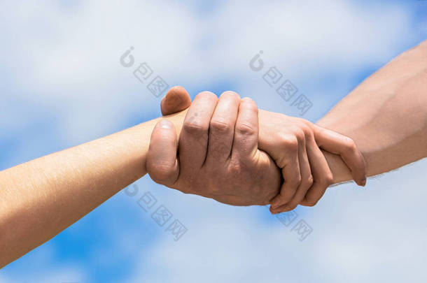 伸出援手。蓝天背景下的男人和女人的手伸出援手。男人和女人的手互相接触，互相支持。团结、同情、慈善、拯救.