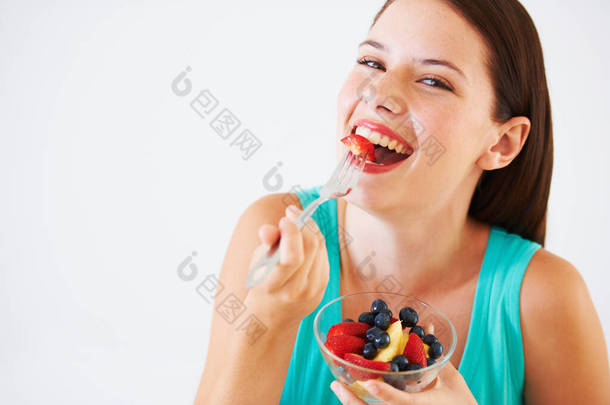 水果沙拉是我的最爱.一个快乐的年轻女人吃水果沙拉的画像