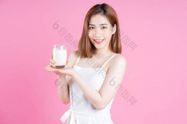 在粉<strong>红背景</strong>下喝牛奶的年轻亚洲妇女形象