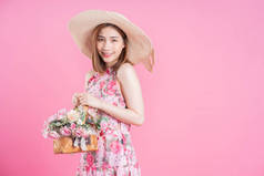 照片上年轻的亚洲女孩穿着粉色背景的花裙子