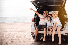 乘坐汽车旅行的家庭乘坐汽车旅行在夕阳西下的暑假旅行，爸爸，妈妈和女儿快乐地旅行，享受假期和放松在一起，享受空气，到达目的地