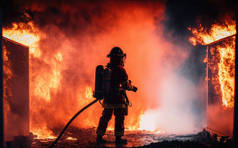 消防员使用旋翼水雾式灭火器与油火灭火，以控制火势的蔓延。消防员和工业安全概念
