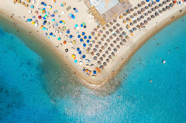 鸟瞰着沙滩上五彩斑斓的雨伞，夏日阳光明媚的大海中的人们。意大利撒丁岛Tuerredda海滩热带景观，绿松石水。旅行和度假。顶级无人机视图