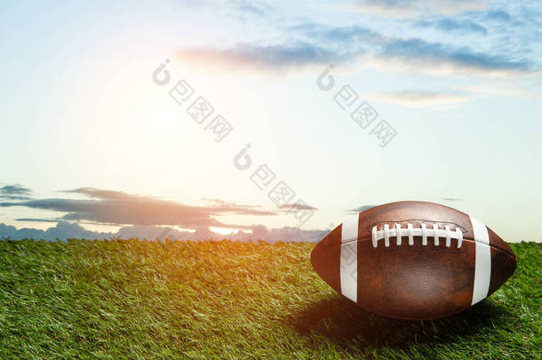 American football ball on green grass field on background of blue sky. Banner with space for text.