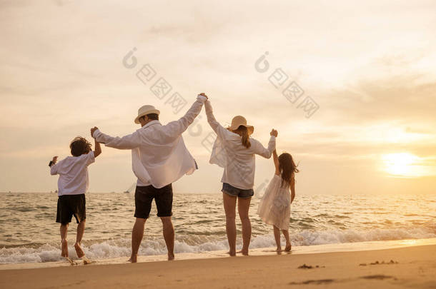 在日落时分，快乐的亚洲家庭在海滩上<strong>欢欢喜喜</strong>地共舞，手牵着手在海滩上<strong>过</strong>着健康的生活，背靠背的人们享受着旅游和度假的理念