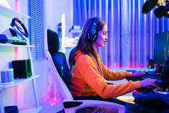 年轻的白种人职业游戏玩家穿着黄色的连帽衫坐在一张椅子上，椅子上有游戏桌、键盘、监视器、麦克风。准备比赛、演艺游戏或录制播客.