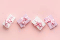 Gift boxes with beautiful bows and confetti on pink background