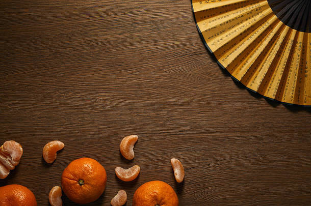 在木制表面的新鲜成熟的橘子和金色的扇子与象形文字的顶部视图