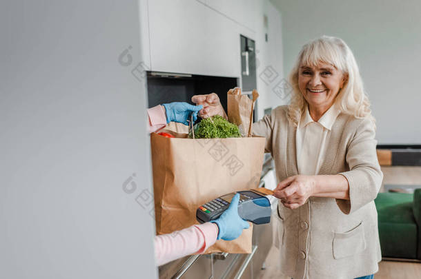 验尸官大流行期间，快乐的老年妇女接受食品交付并以信用卡和终端付款