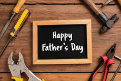 快乐父亲节的文字在黑板上，旁边有工具和领带的边框，背景是乡村木料