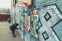 男性街头画家画墙上五颜六色的涂鸦