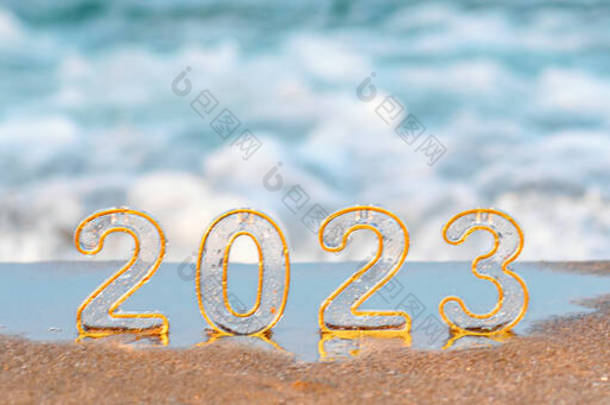 Happy new year 2023 wide banner, background. Numbers 2023 on golden sand of beach and blurry sea wav