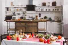 感恩节有沙拉、玻璃杯、蜡烛、蔬菜、胡椒磨、玉米、盐磨和南瓜的桌子