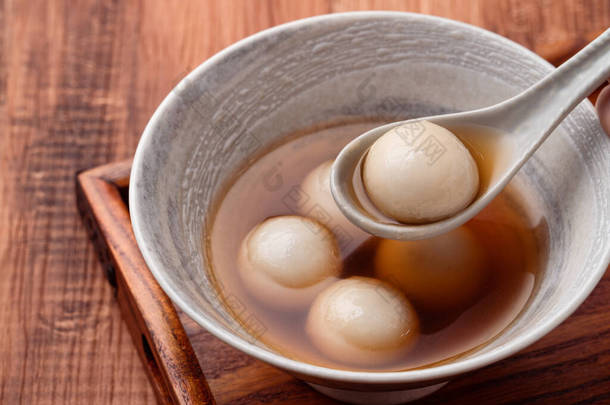 将芝麻大汤圆（汤圆，糯米团）与甜糖浆汤放在木碗里，放在木桌上，作为<strong>冬至</strong>佳肴.