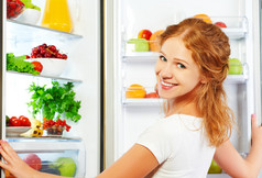 幸福的女人与水果、 蔬菜和他打开冰箱