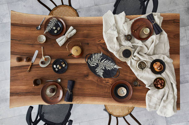 餐厅的室内设计风格新颖，有木制核桃木餐桌、复古椅子、餐具、盘子、桌布、茶壶、食品、装饰和典雅的配饰。水泥地面。模板。顶部视图.