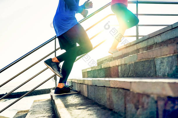 夫妇跑在台阶在日落-朋友做锻炼会议锻炼到<strong>楼梯</strong>室外-接近人<strong>奔跑</strong>的腿-体育, 健康, 生活方式人概念